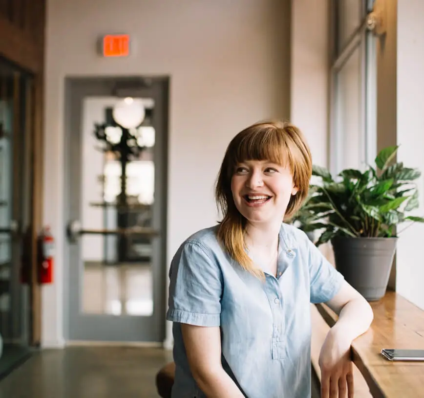 young woman smiling whilst sitting at a desk